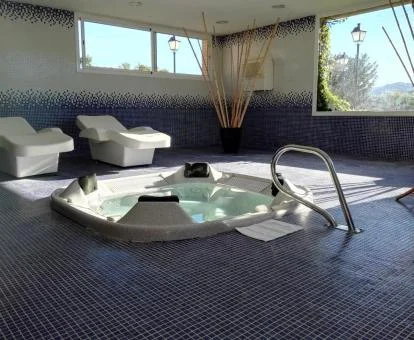 Acogedora sala de bienestar del spa con vistas a la naturaleza, jacuzzi y tumbonas de piedra.