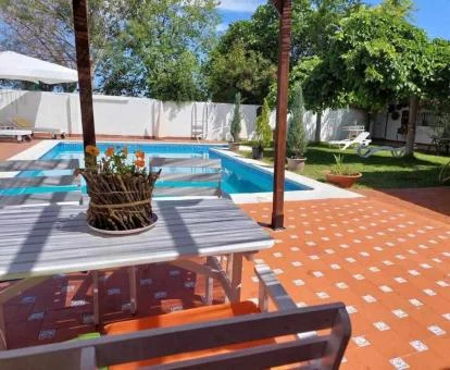 Bella zona exterior con comedor, jardín y piscina al aire libre.