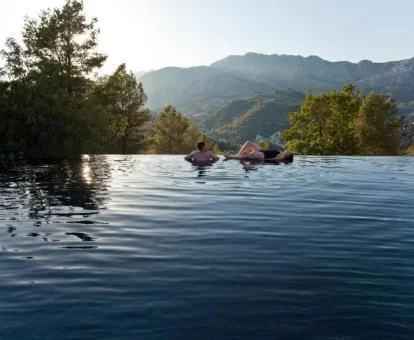 Pareja disfrutando de la piscina con borde infinito y espectaculares vistas a las montañas de este hotel solo para adultos.